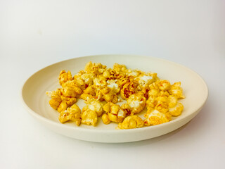 Sweet caramel popcorn on round plate, isolated on white background.