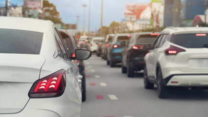 Rear side of white car and turn on brake light. Traffic is congested and there are long queues in...