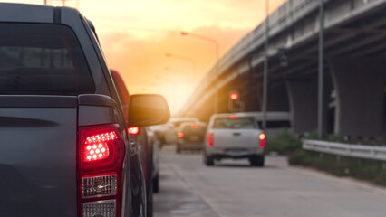 Rear side of pickup car grey color. Traffic jam on the road at sunset. Blurred background of other car with light brake and cement bridge.
