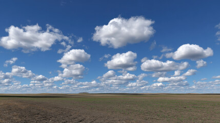 Obraz premium Vast landscape features clear blue sky adorned with fluffy white clouds, casting soft shadows over expansive, open field below. scene evokes sense of tranquility and freedom