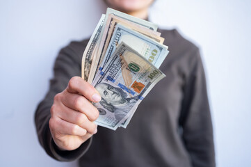 Cropped shot view of woman holding various of American dollar banknotes in hands. The US Dollar is...