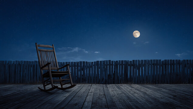 Empty wooden rocking chair sits on a deck under a full moon at night