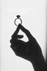 Shadow silhouette of hand holding engagement ring proposal concept