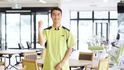 介護施設でガッツポーズをするアジア人介護福祉士