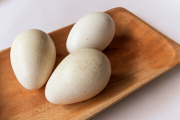 Group of three fresh turkey eggs on a wooden plate