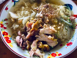 close up of a bowl of soto ayam with chicken meat and savoury broth
