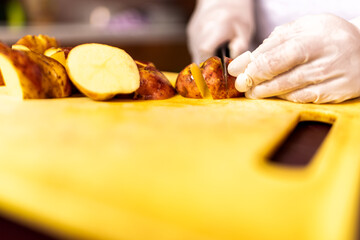 Chef's hands slicing potatoes on cutting board