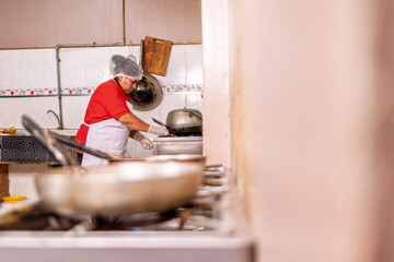 Woman cooking fried food in small restaurant kitchen