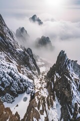 Snowy rocky mountain peaks emerging from dramatic fog in winter alpine landscape