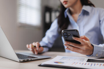 Businesswoman working with laptop and smartphone in office