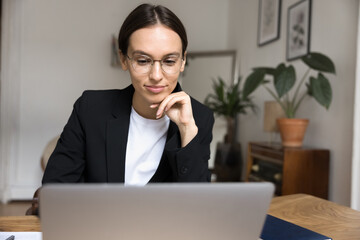 Confident young businesswoman look at notebook screen with light smile