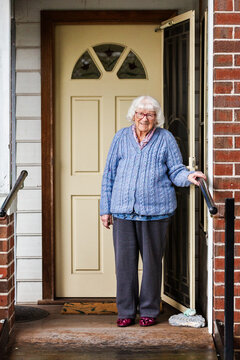 Portrait of 99 year old elderly Australian woman standing by front door of her home