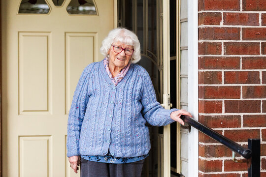 Portrait of 99 year old elderly Australian woman standing by front door of her home