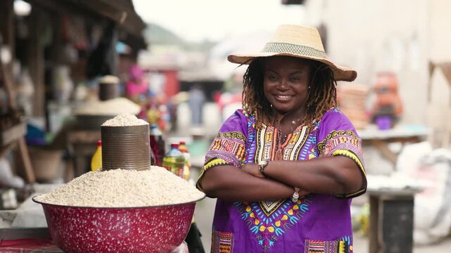 Portrait of Small business owner, SME. Local traditional African market woman in a purple dashiki and straw hat at her vibrant outdoor market stall.