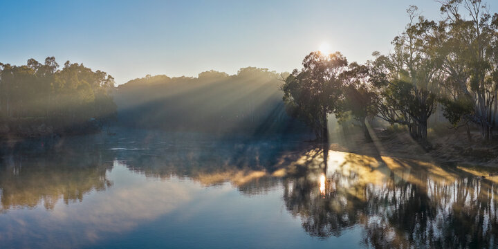 Aerial panorama of rays of sunshine through fog over gumtrees along the Murray River at Moama