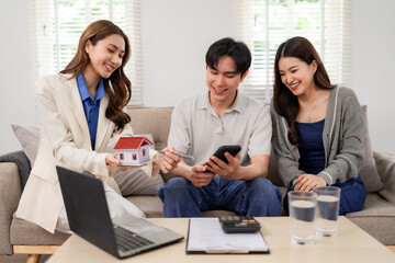 Asian real estate agent advising young adult couple home property investment residential consultation living room buying selling house market expert advice