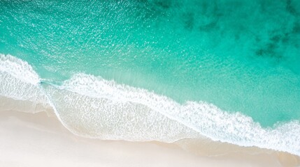 Obraz premium Aerial view of turquoise ocean waves gently meeting a pristine white sandy beach