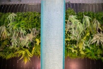 Water is streaming down on semi-transparent acrylic square pillar wall peacefully and calmly.