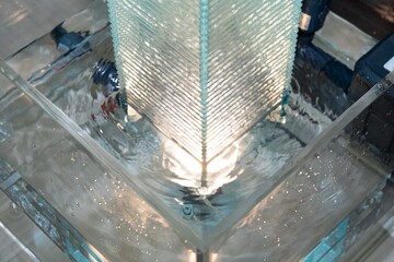 Water is streaming down on semi-transparent acrylic square pillar wall peacefully and calmly.