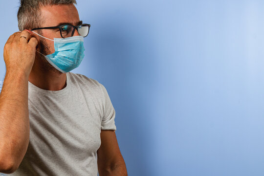 Man wearing a surgical mask adjusting it while looking right - Powered by Adobe