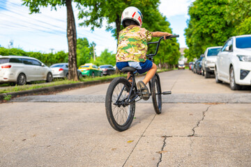 Obraz premium Little asian boy enjoy bicycle practice in city village town house road