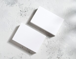 Clean white business cards laid on textured concrete surface with natural light shadows