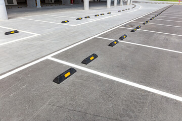 empty places in a parking lot with black rubber wheel stoppers.
