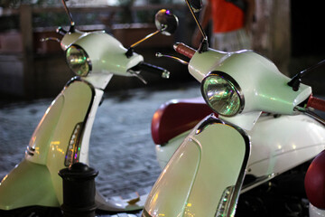 Two retro scooters with round headlights at night on the street