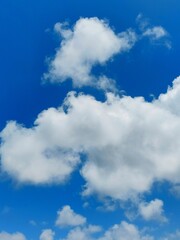 Soft cumulus clouds against a clear summer sky background.