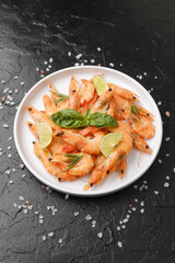 Shrimp with herbs and coarse salt on black surface for cooking background or seafood concept