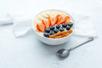Balanced oatmeal breakfast with fruit and almond topping on cloth with spoon