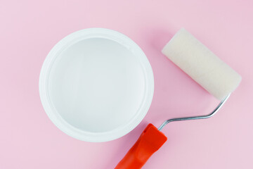 Obraz premium Open white paint bucket and roller on pink background for DIY painting supplies and preparation concept