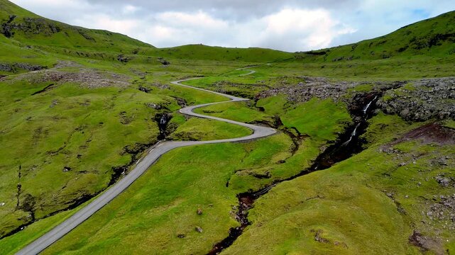 Explore the breathtaking winding road nestled amidst the verdant hills of the Faroe Islands.