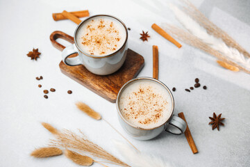 Two cups of coffee with cinnamon and anise on a table with dried grass