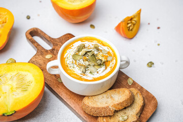 creamy pumpkin soup with seeds and bread on wooden board