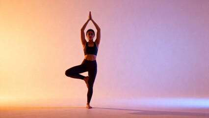 Woman practicing tree pose in yoga against a gradient background