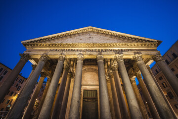 Fototapeta premium Pantheon in Rome illuminated at night with its grand columns and ancient inscription against a deep blue sky