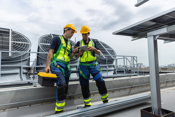 Engineers with safety gear inspect rooftop HVAC and solar panel systems for energy efficiency. Industrial maintenance, clean energy, and facility management concept. © eakgrungenerd