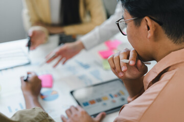 Young professional team planning project strategy around charts and tablet, collaborative creative meeting with focused discussion