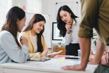 Young professional team brainstorming around desk with tablet and sticky notes, collaborative creative planning and focused discussion