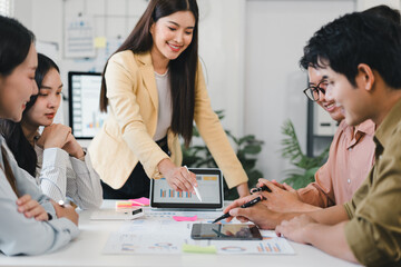 Young businesswoman leading team meeting around table, collaborative planning and smiling while reviewing charts and tablet
