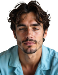 A young man with curly, dark hair sits comfortably indoors, looking directly at the viewer with a relaxed expression. His blue eyes reflect a calm atmosphere, creating a thoughtful vibe.