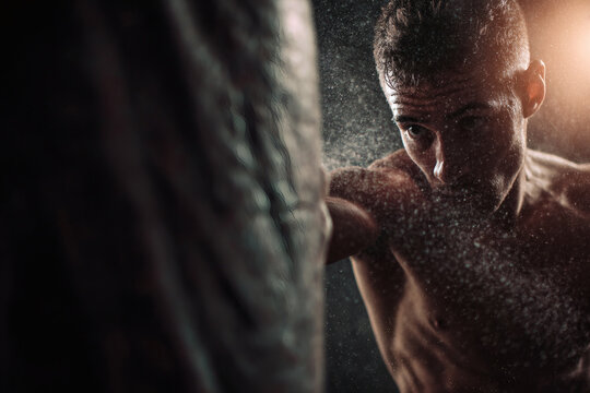 Powerful Boxer Striking Heavy Bag with Dust in Motion - Powered by Adobe