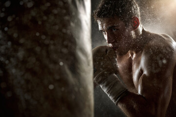 Powerful Boxer Striking Heavy Bag with Dust in Motion