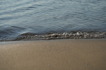 Peaceful seaside landscape with gentle waves, sand beach, and distant mountains. Calm coastal scenery symbolizing relaxation, travel, and natural beauty.