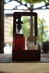 Bottles of olive oil and vinegar in wooden holder on restaurant table – close up of condiments set with glass bottles, seasoning, sauces for cooking, dining and gastronomy background