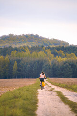 Fototapeta premium Woman cycling along rural forest path