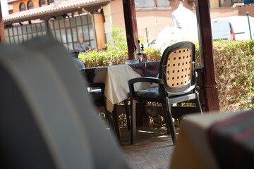 Cozy outdoor café terrace with empty tables and chairs under the shade. Sunny day in a European street restaurant. Perfect for travel, tourism, and lifestyle concepts.