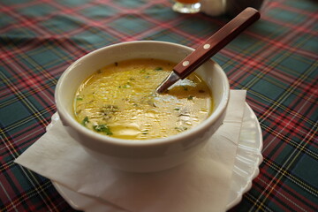 Chicken soup in bowl with spoon – hot homemade broth with herbs close up, traditional healthy food for lunch or dinner, comfort meal background, family cooking and restaurant cuisine concept