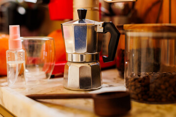 Moka pot on the table at home. Coffee making concept.  Moka pot, bean spray, coffee grinder, jar of coffee beans standing on the kitchen table.